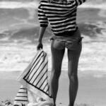 A girl holding a mat, standing near beach