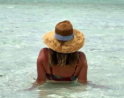 A girl wearing a cap sitting inside water
